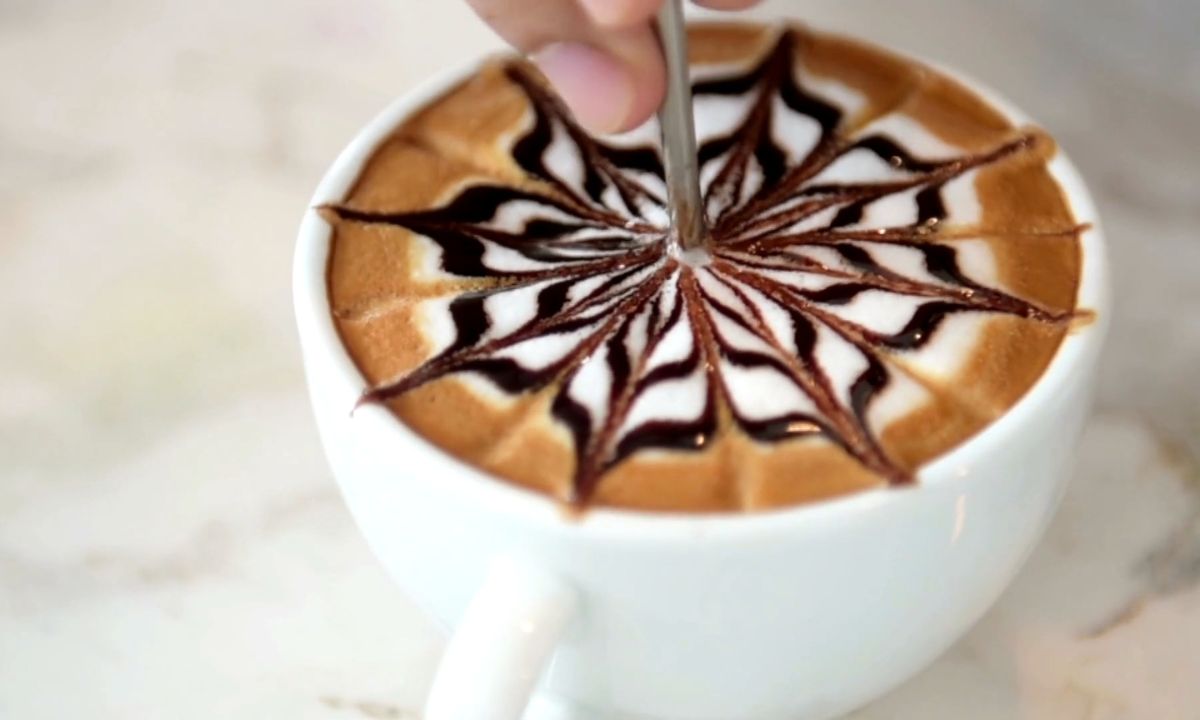 osoba dekoriše šoljicu moka kafe sa topingom od čokolade