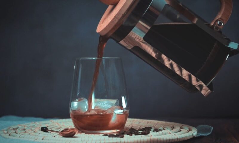 osoba dodaje kafu u čašu sa ledom